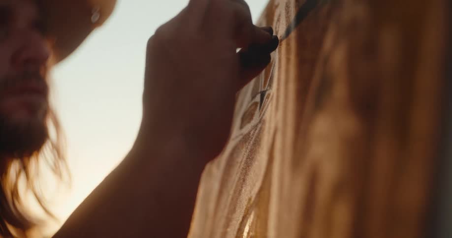 Man focuses while drawing on a surface illuminated by sunlight