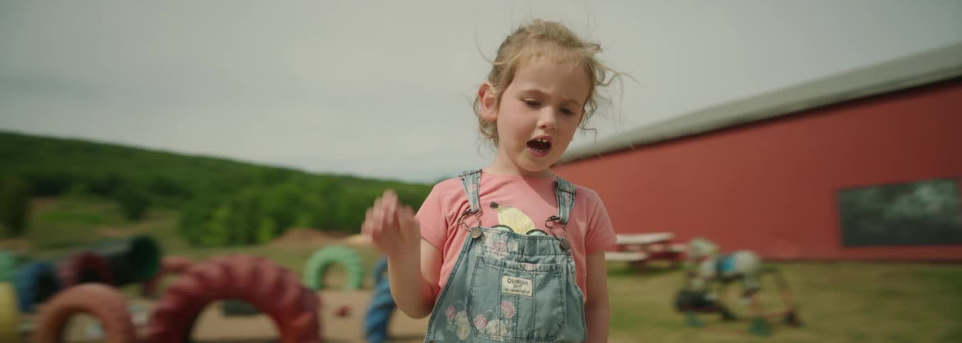Child with closed eyes brings a hand to the face in an outdoor area