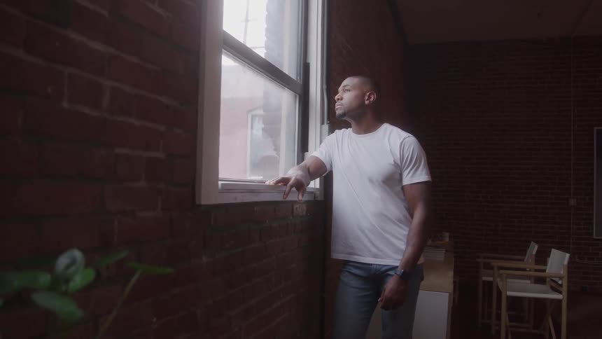Man leaning on a windowsill looking outside