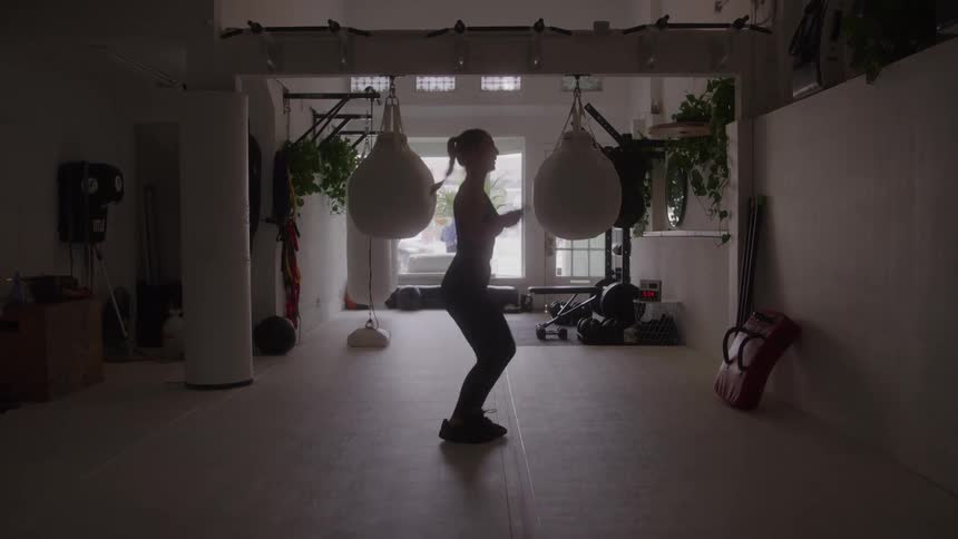 Woman exercises in a gym with a view of the street during the daytime