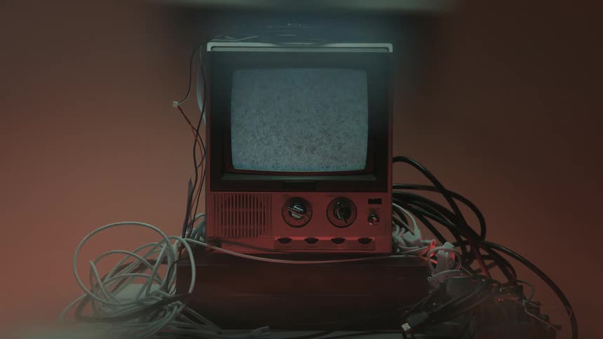 Person turns dial on vintage device surrounded by cables in lit setting