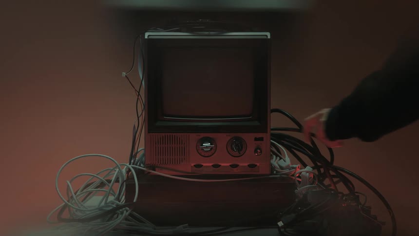 A television set displaying visual noise that disappears when a human hand reaches in to turn it off