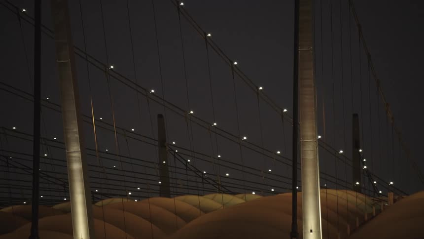 Illuminated cables and metal structures standing out against the night sky