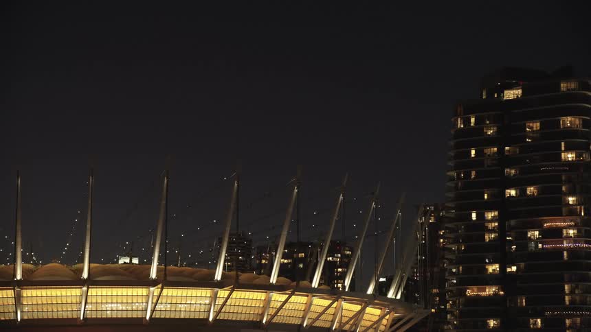 Strings of lights attached to spikes twinkle on a downtown building at night
