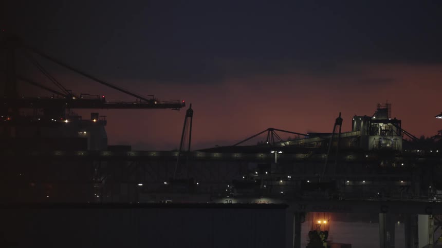 Illuminated cranes operate at the port during dusk