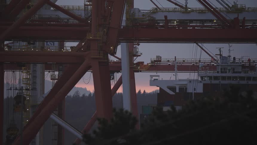 Port cranes operating at sunset with a ship in the background