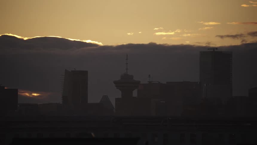 Timelapse of a city skyline silhouette of buildings at sunset under a partially cloudy sky