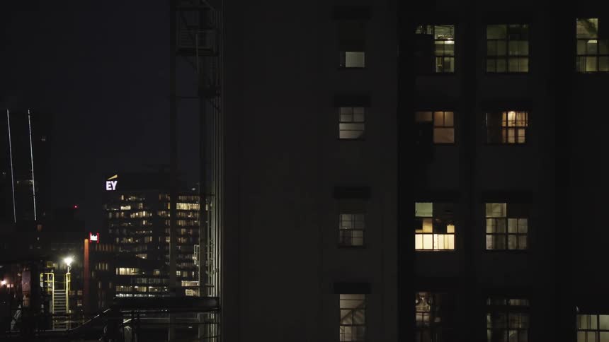 A city highrise glows at night its windows illuminated against the dark sky