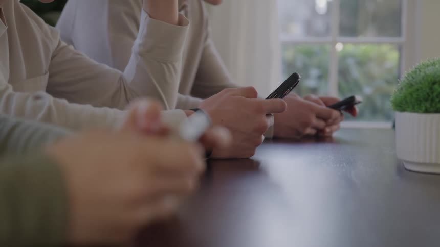 People side by side using their phones on a table