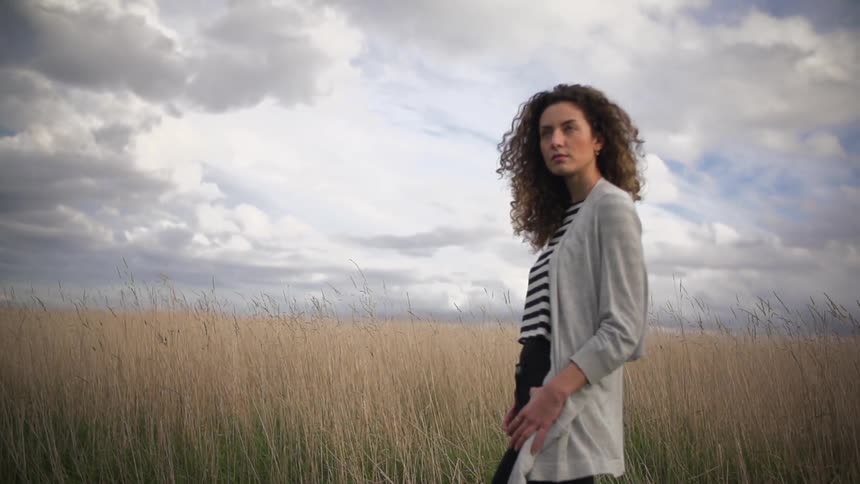 Woman walking in a field on a cloudy day