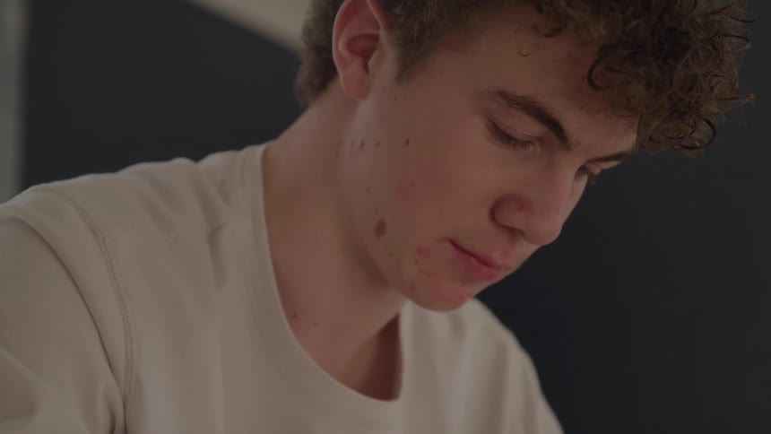 The teenager is sitting and looking down