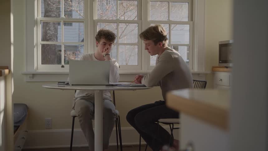 Two men focused on working on a laptop at a table