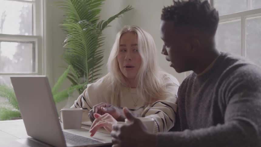 Couple talking while analyzing something on a laptop screen