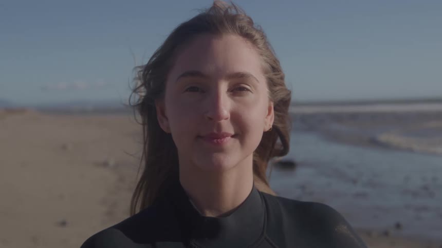 Woman smiling on the beach wearing a wetsuit