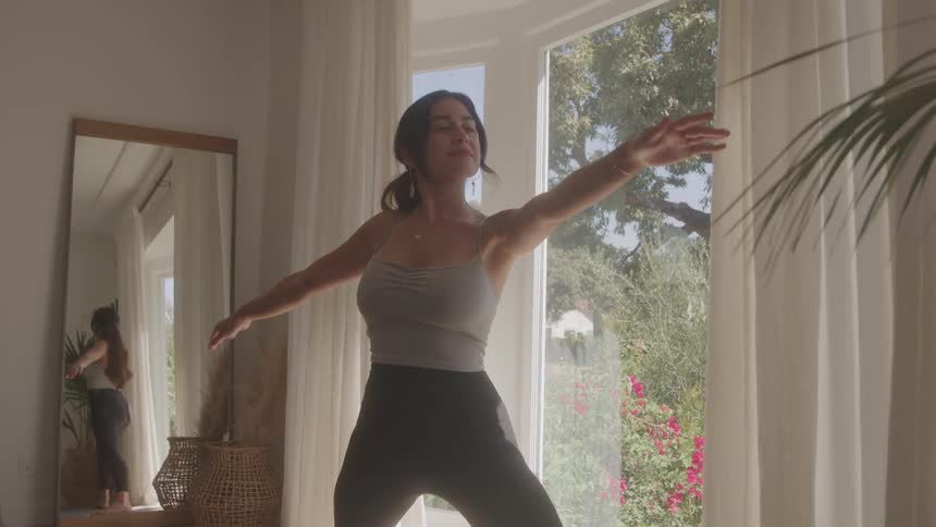 The woman does yoga in front of a mirror