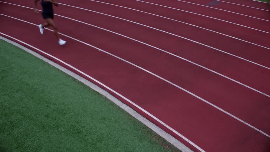 A woman athlete sprints on a stadium track