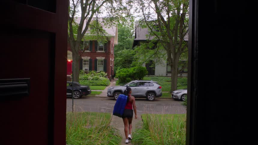 The woman leaves the home while carrying a bag