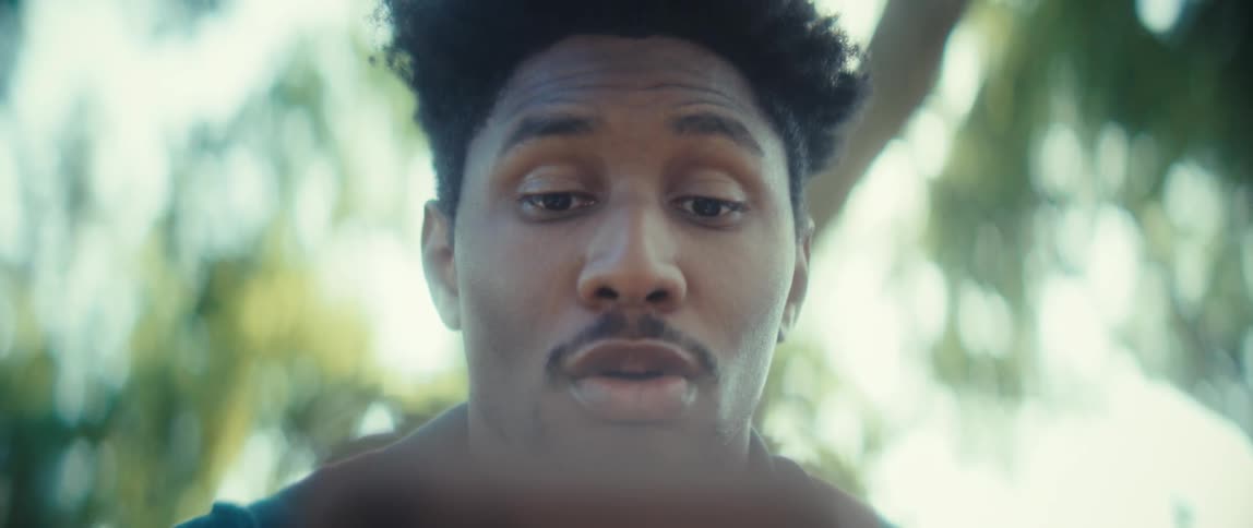 Close up of a young black man making happy faces while using an electronic device outdoors during daytime