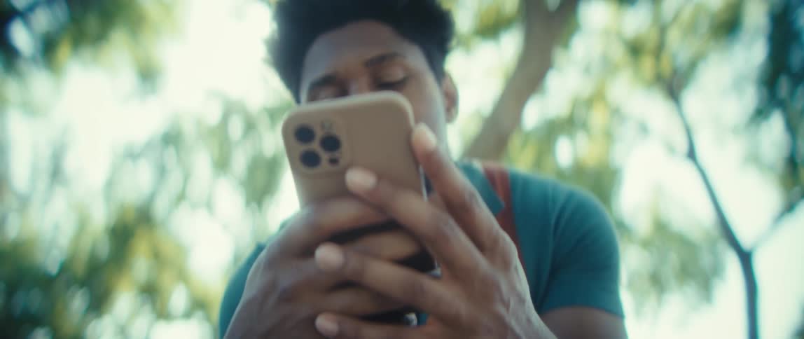 Man smiling while looking at his phone under sunlight