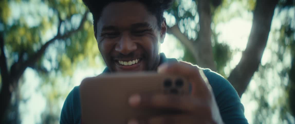 Man looks attentively at the phone outdoors with sunlight in the background