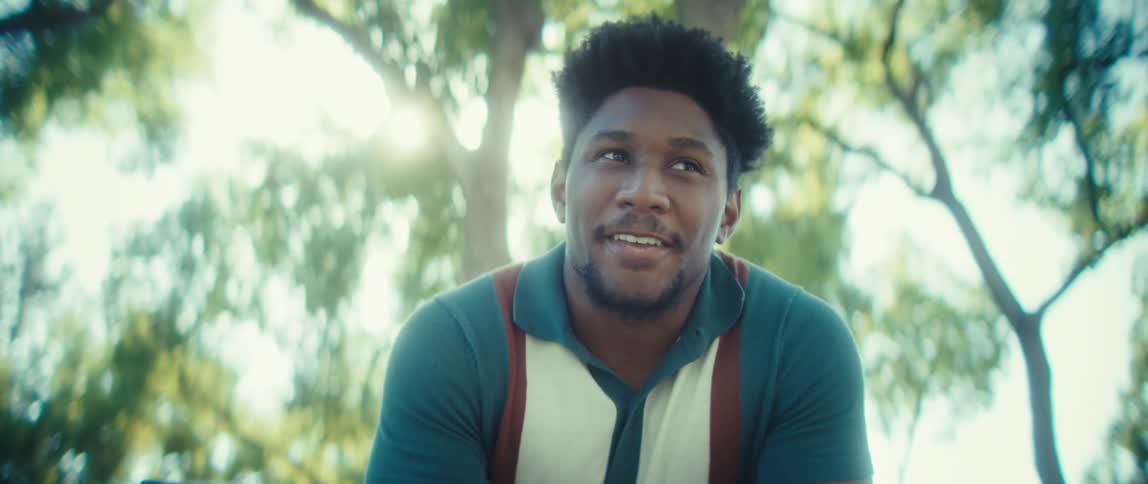 Man smiling while interacting with his phone outdoors