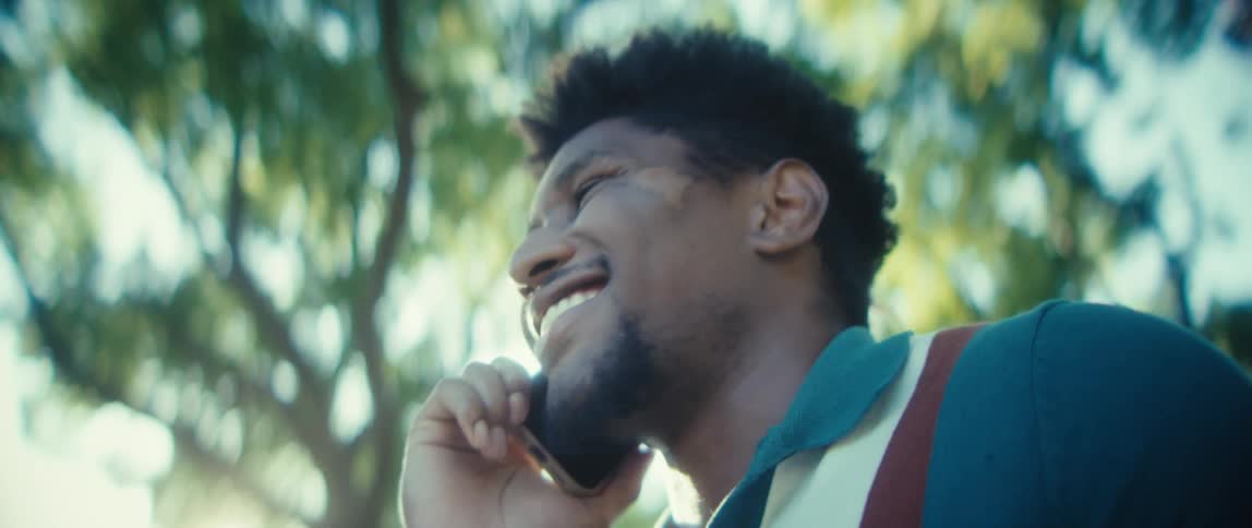 Man smiling while talking on the phone outdoors