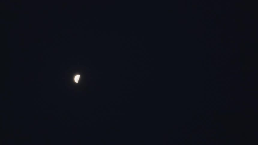 The half moon shines in the sky