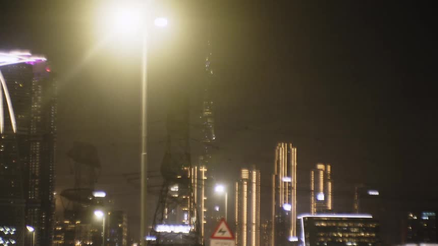 Transmission towers stand amid a brightly lit city at night