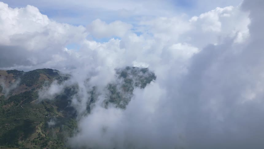 Aerial view of lush green mountains shrouded in clouds and fog