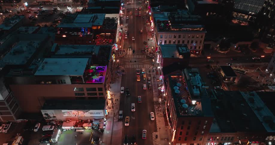 Aerial view of a busy city street with lit buildings and traffic at night
