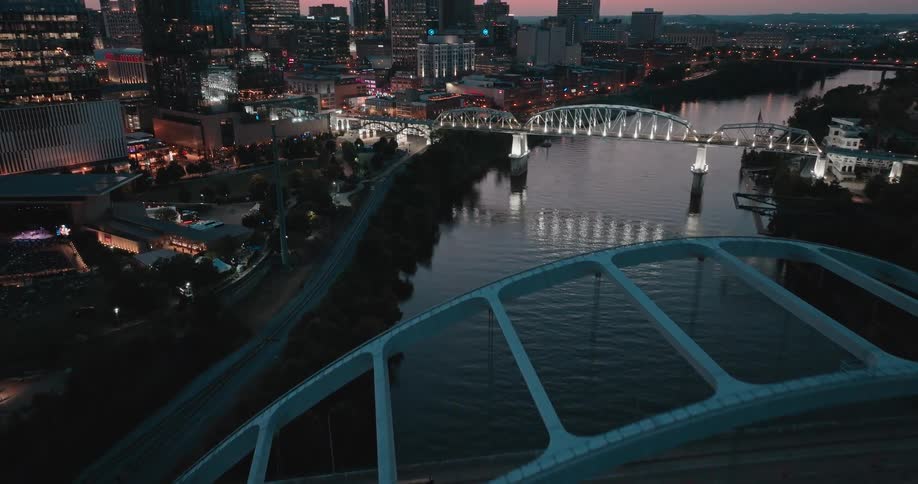 A city skyline at night illuminated by building lights with a series of connecting bridges where cars pass by