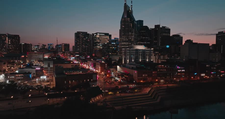 Illuminated bridge over the river leading to the urban skyline at dusk