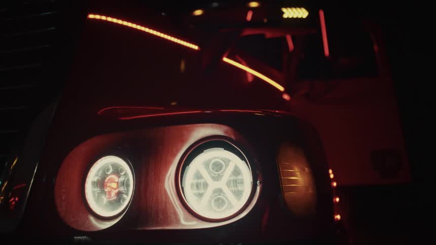 Closeup of a semis illuminated led headlights and accent strips glowing red in the dark