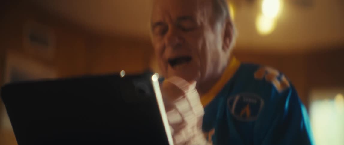 Elderly man clapping while watching on a tablet