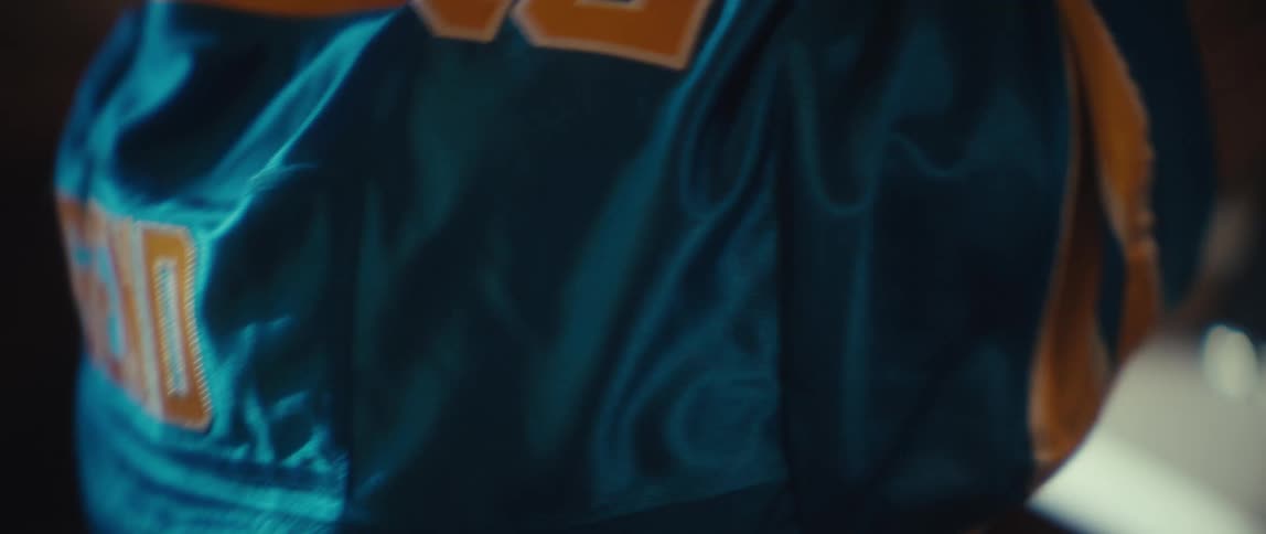 A close view video focuses on the back of a person wearing a bright blue sports jersey with yellow trim and lettering showing the word legend and a number 92 stitched onto the fabric