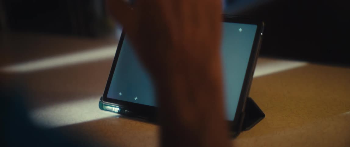 A person is moving their arms and clapping at a softly glowing tablet on a stand suggesting eager anticipation