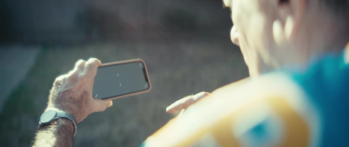 Elderly man outdoors interacting with a smartphone