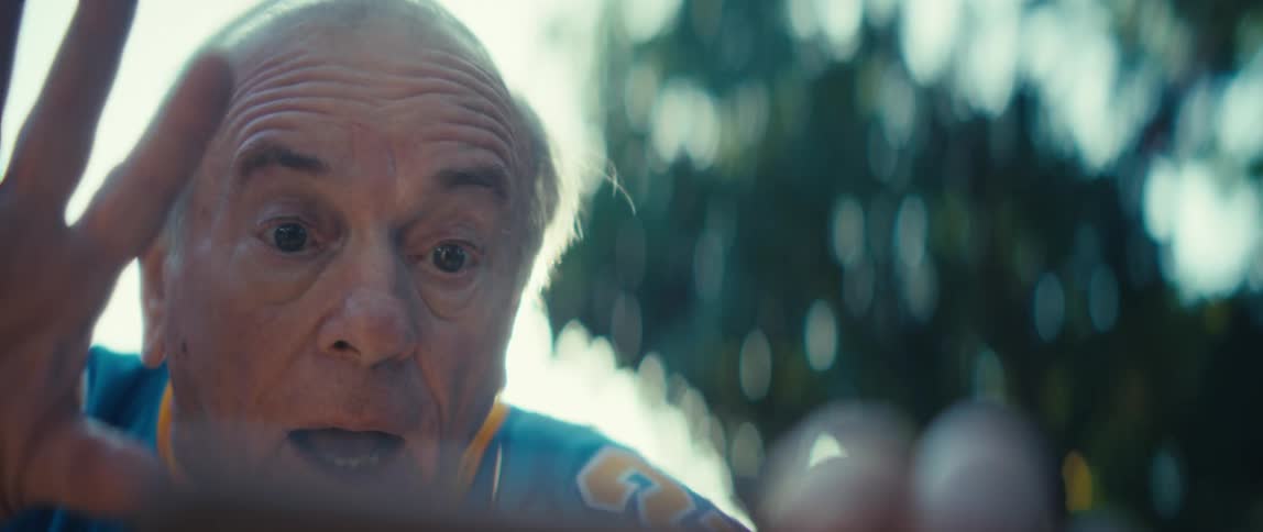 Elderly man outdoors focused watching on a smartphone