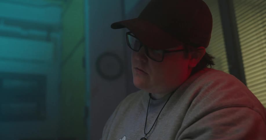 Close up of a young man typing while using a laptop on a table in a room