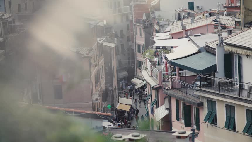 Narrow street filled with people is surrounded by colorful buildings with balconies and awnings