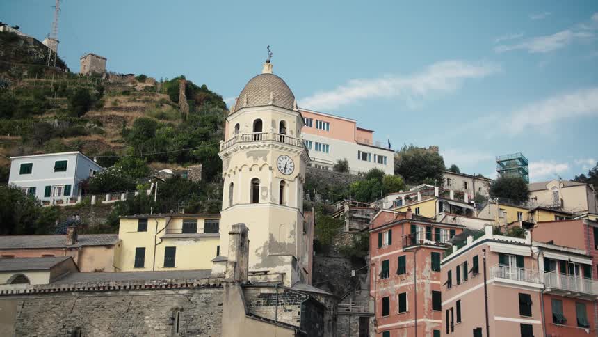 Clock tower in a coastal village surrounded by colorful hillside houses