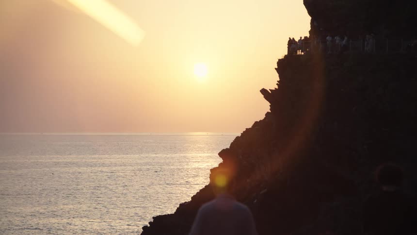 People watching the sunset from the top of a seaside cliff