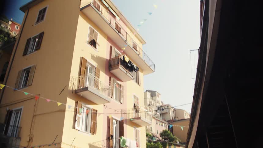 A busy street on a sunny day with people walking by and a fourstory yellow building standing on the side