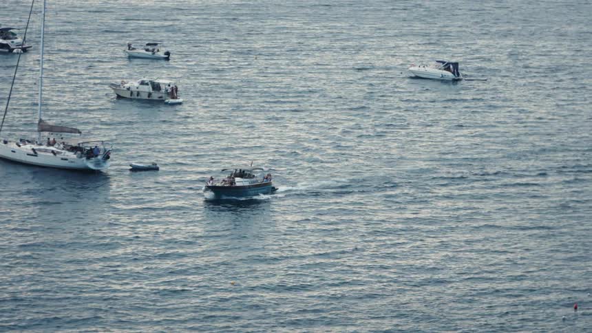 Several boats sailing and anchored on calm waters