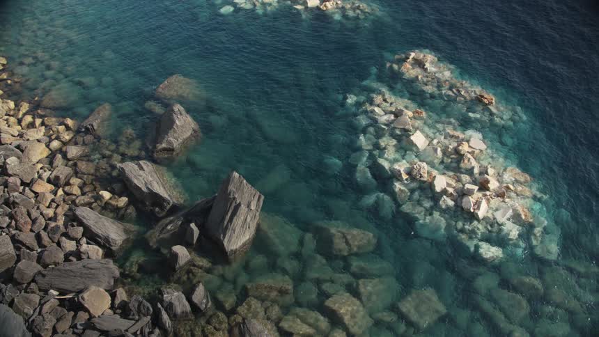 Aerial view of clear blue water along a rocky coastline