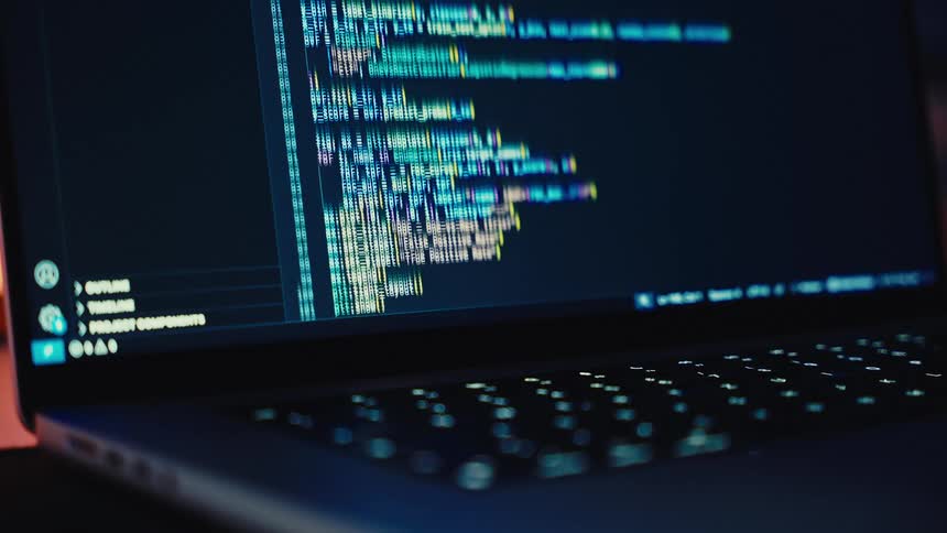 Computer code scrolls on the screen of a laptop