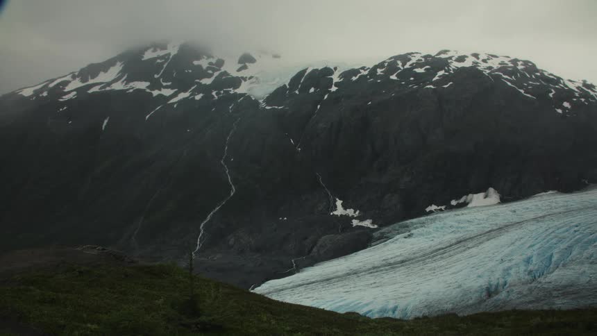 A mountain with snow on its peak and lots of snow and ice at its base