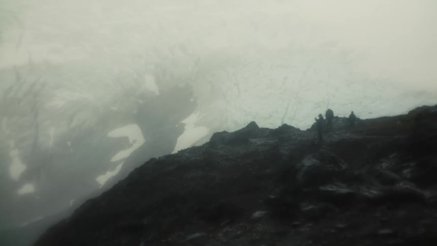 Four people on a mountain in winter observing glaciers from above
