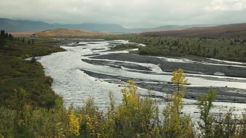 River winds through a wide plain surrounded by vegetation and distant hills