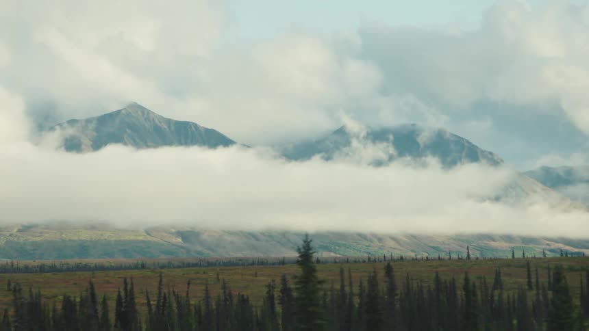 Mountain range covered in fog next to a lain area and a forest area outdoors during day time